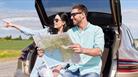 2 people holding map in boot of car