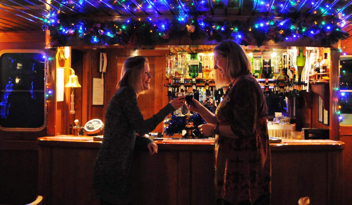 Two ladies at the bar with mulled wine and Christmas lights