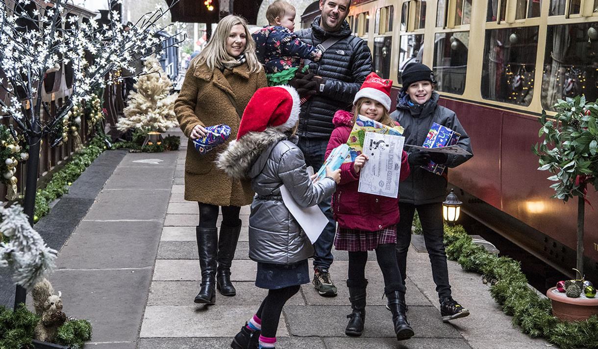 Family dresses up for Christmas next to a steam train