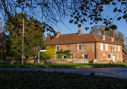 Jane Austen's House from the garden in Autumn.  Brown and orange leaves carpet the ground.