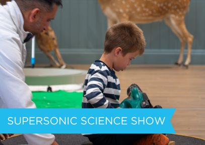 Child sitting on a hoover vacuum at a science demonstration.