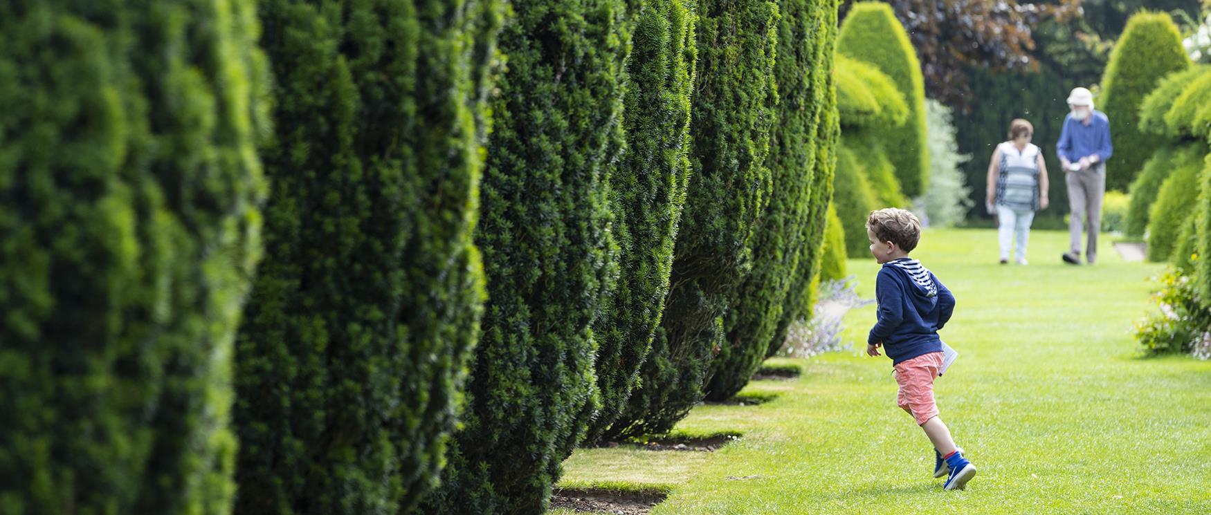 50 things to do this summer - child running through trees at Hinton Ampner, Hampshire