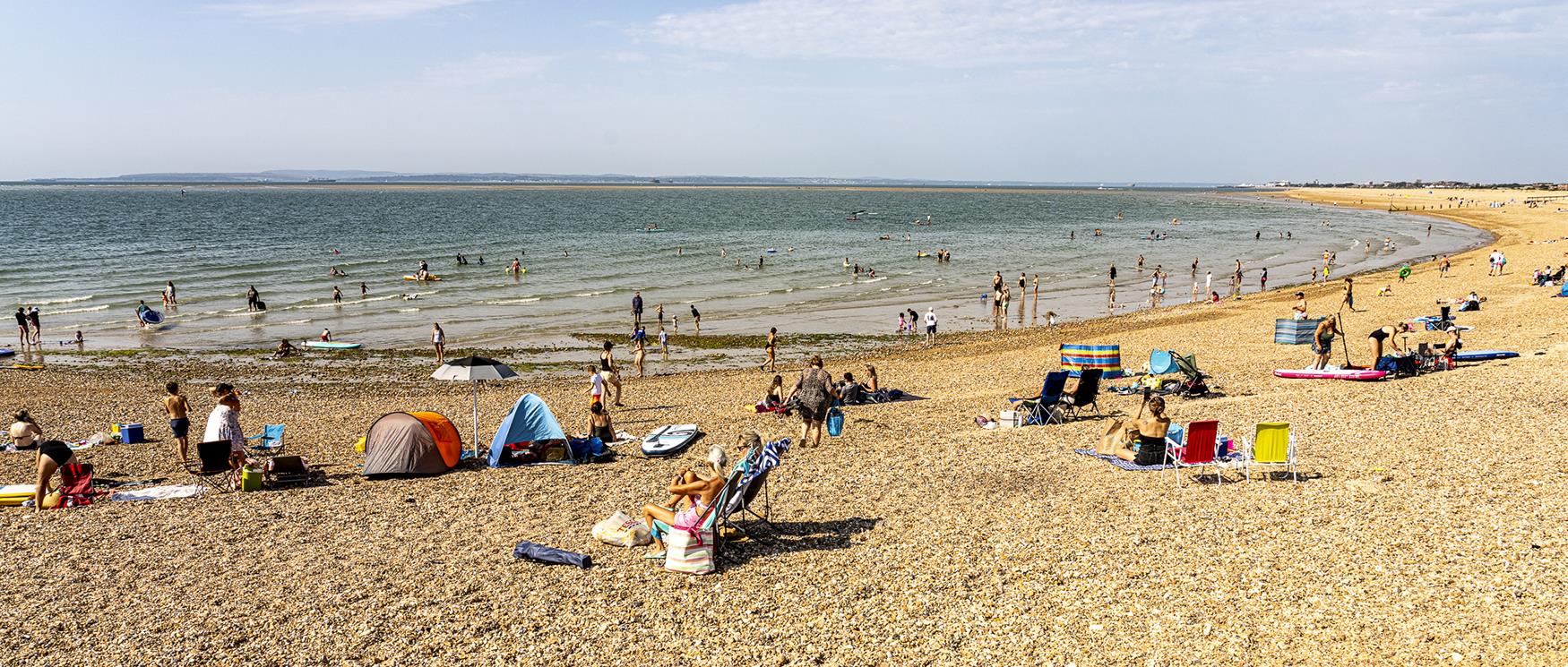 People sit on pebble beach at Hayling Island, Hampshire