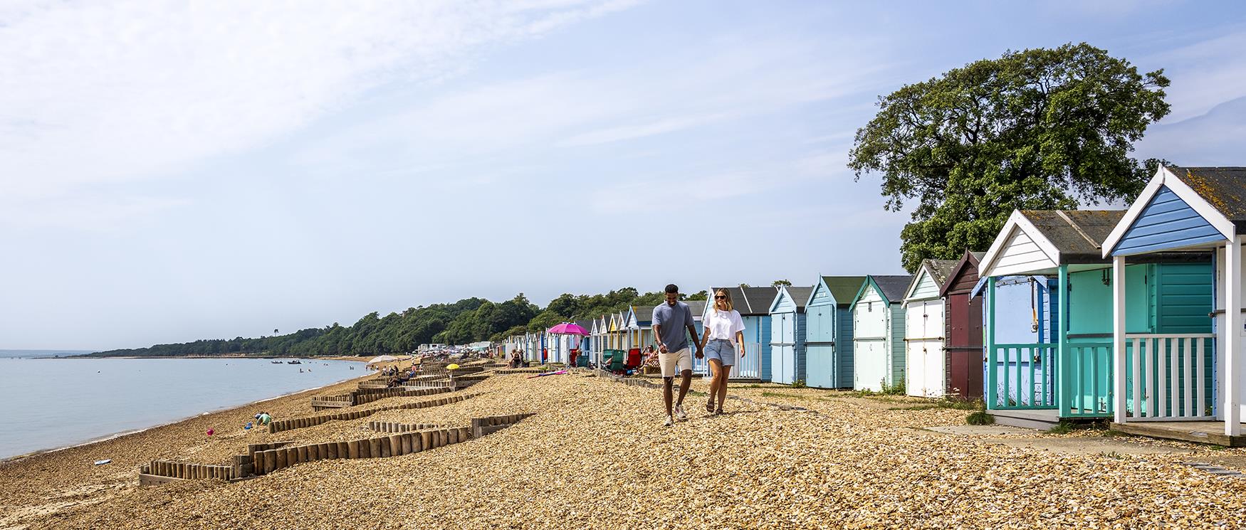 Couple walk along pebble beach at Lepe, Hampshire