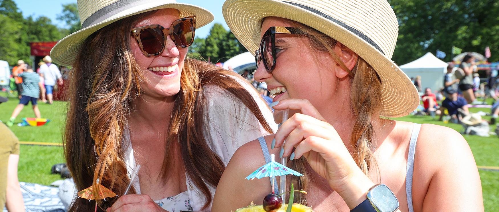 Two women enjoying pineapple cocktails outdoors at Winchester Foodies Festival