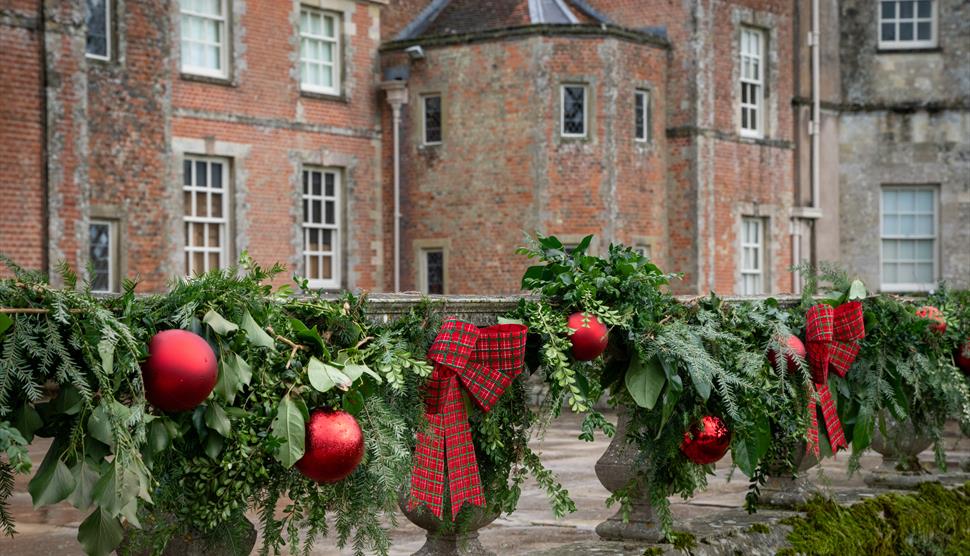 A red brick house with a Christmas garland in front
