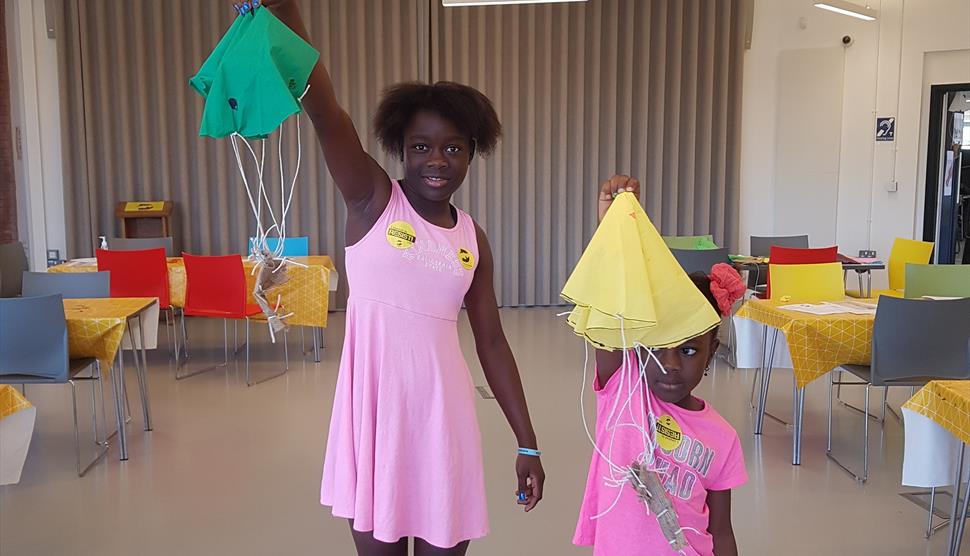 Two girls at The D-Day Story showing off the parachutes they've made