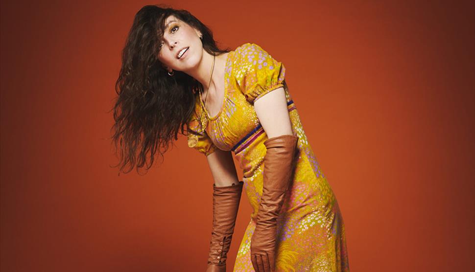 Bridget Christie in a gold dress for the promotional shot of her latest tour: Jacket Potato Pizza