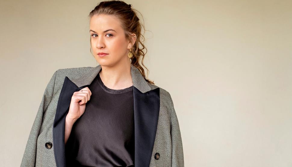 Conductor Charlotte Corderoy stood in front of a blank beige background