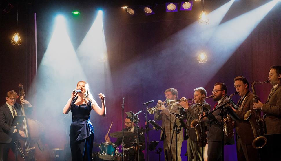 A female singer with a jazz band behind her