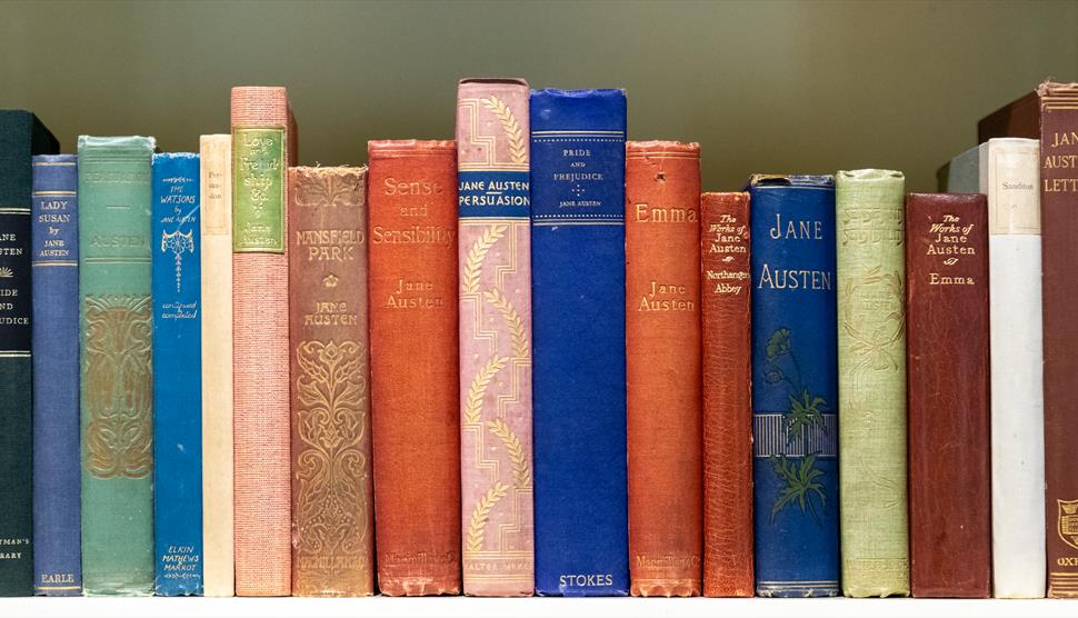 Jane Austen novels in a row on a bookshelf.
