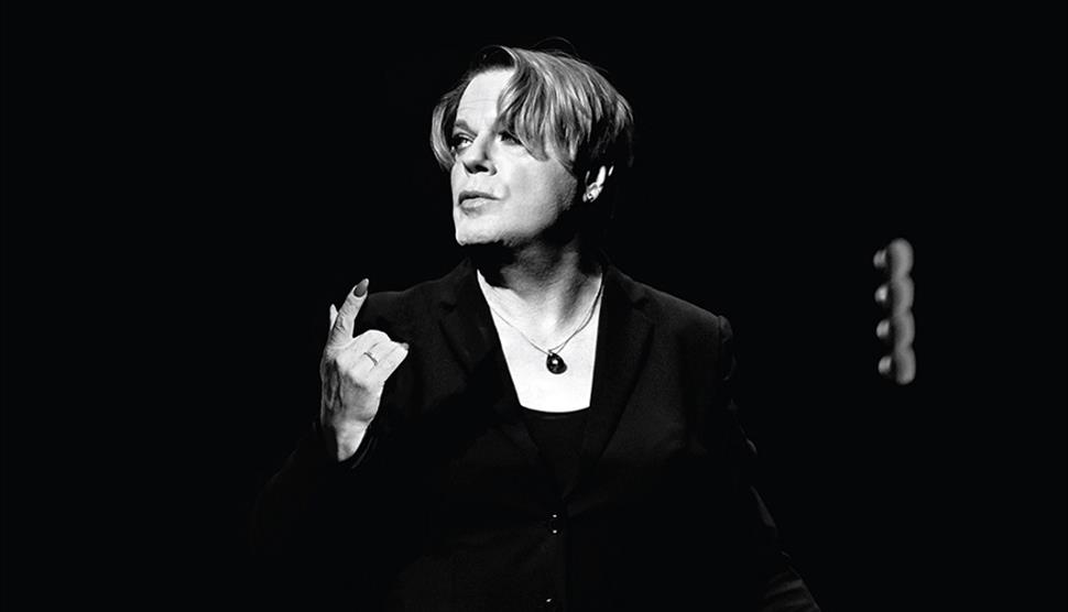 A black and white picture of Eddie Izzard on stage.