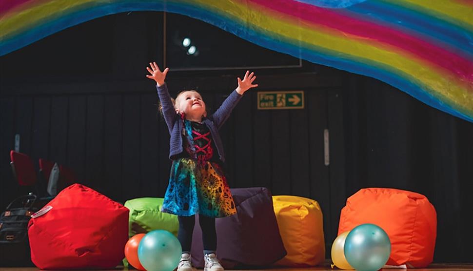 Press shot for Filskit Theatre: Wonder Gigs. featuring a small child listening to music in multicoloured surroundings.