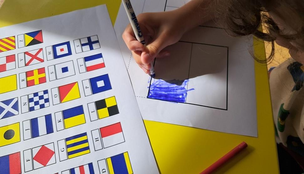 A child colouring in flag sheets to spell out a name