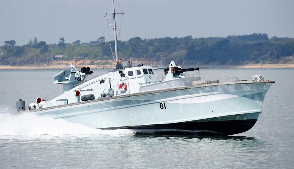 Motor Gun Boat 81 racing across the Solent at speed, cutting through the water with spray trailing behind its sleek WWII hull.
