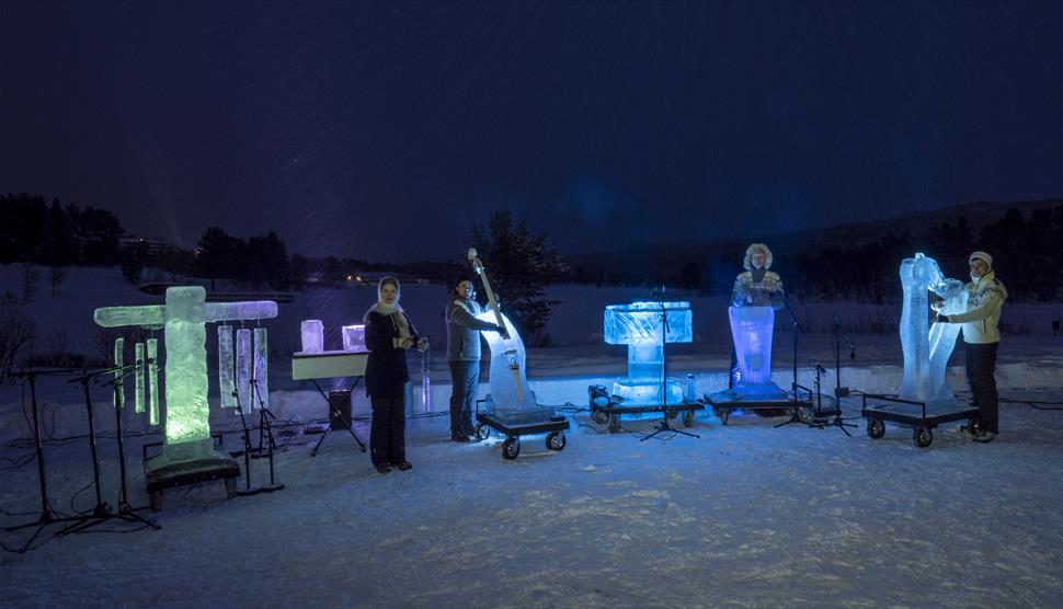 Four performers stand in a line with various ice instruments..