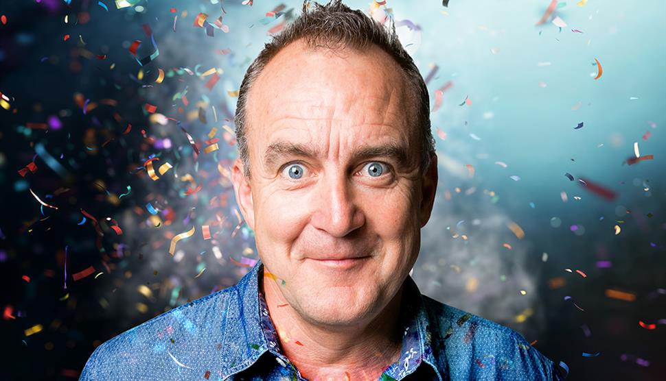 Head and shoulders shot of comedian Jimeoin with confetti around him.