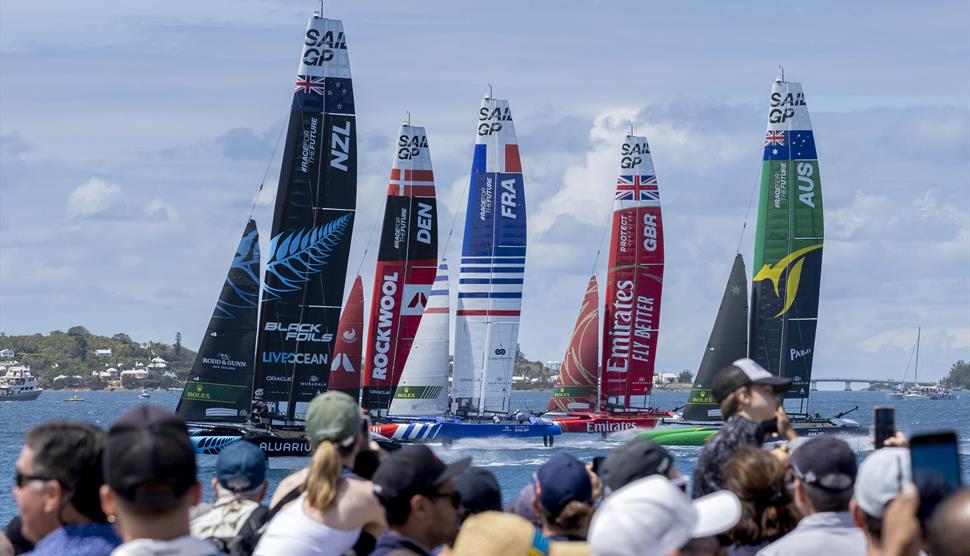 Image of F50 catamarans racing on water with crowd watching in the foreground