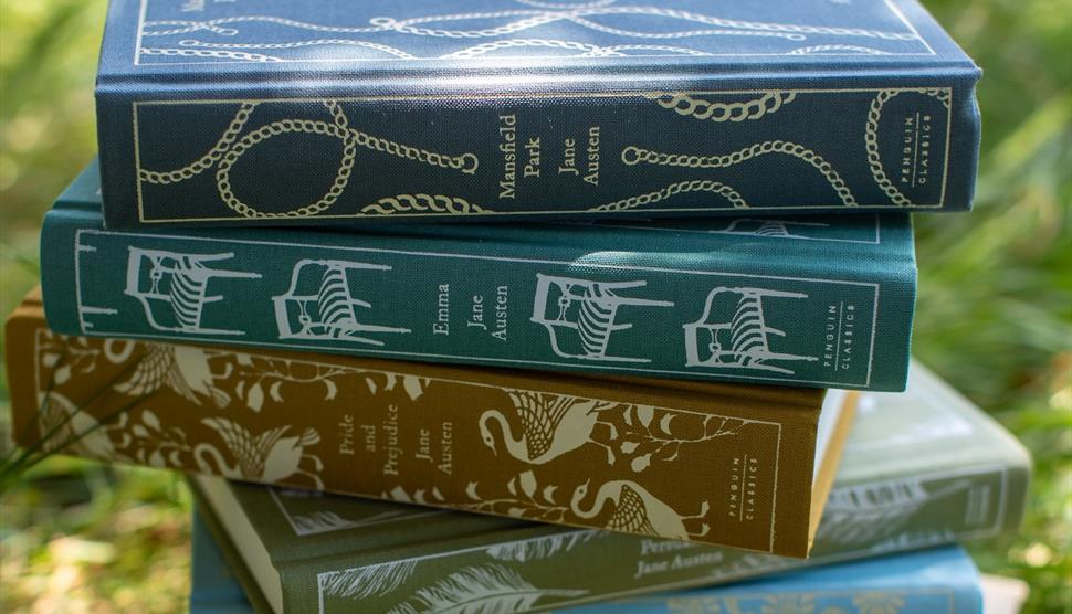 Beautiful clothbound editions of Jane Austen's novels stacked on the grass in Jane Austen's garden