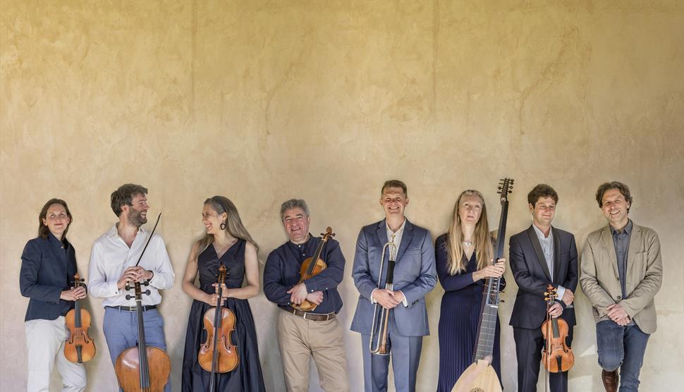 A group of musicians holding various string instruments stand in a line.