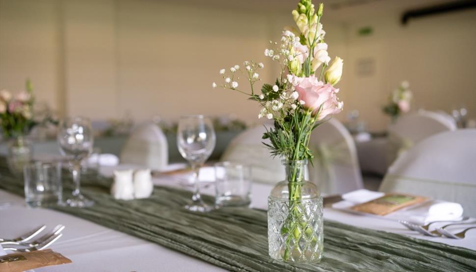A vase of pink roses sat on a neatly set table