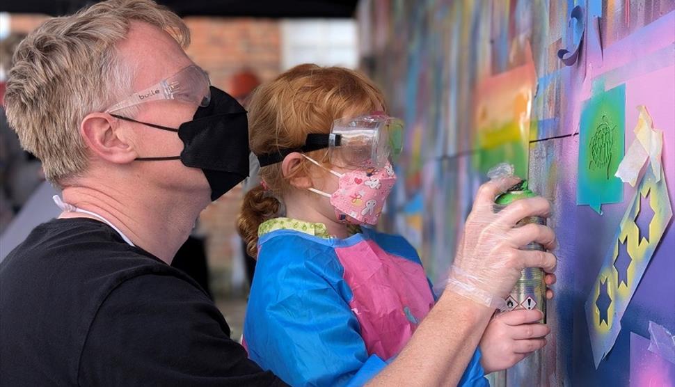 A child and adult spray painting