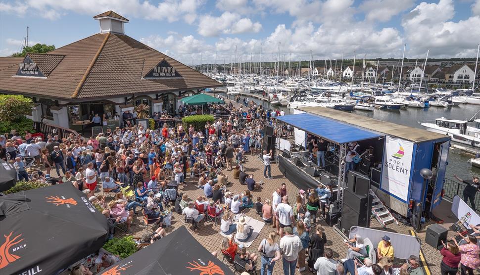 Aerial shot of a stage set up at The Boardwalk in Port Solent, with people gathered all around to watch.