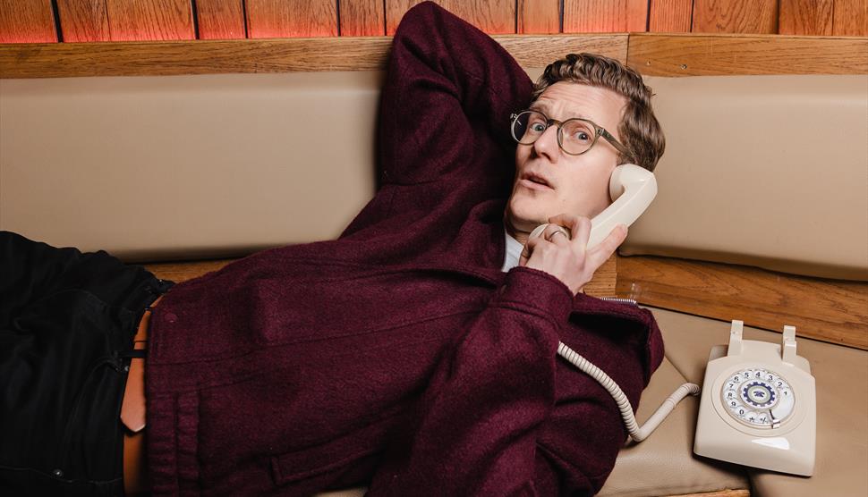A man lying on a sofa holding a phone