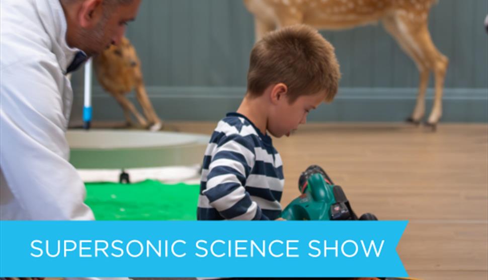 Child sitting on a hoover vacuum at a science demonstration.