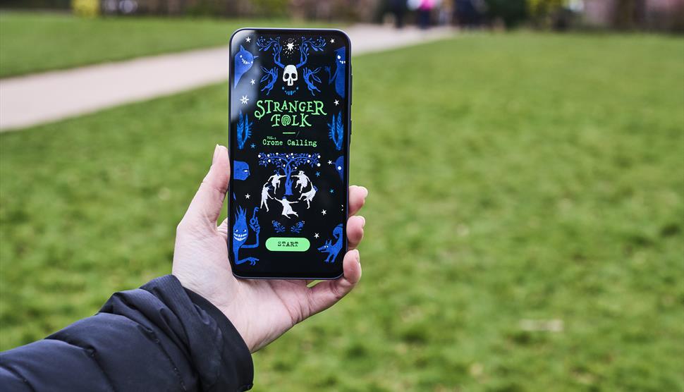 A hand holds a mobile phone with the event app open.