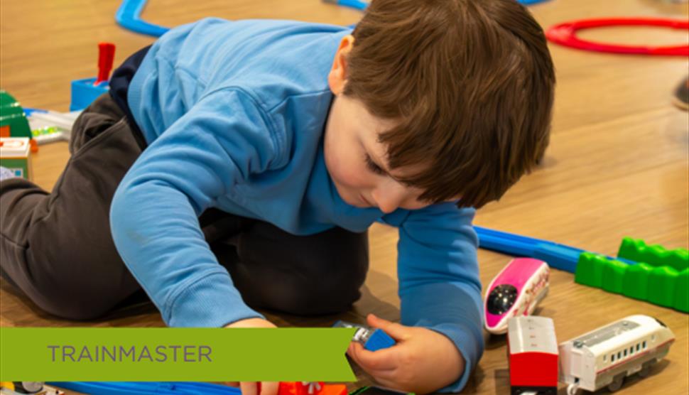 Young Toddler playing with toy train on tracks at October half term event held at Sky Park Farm.
