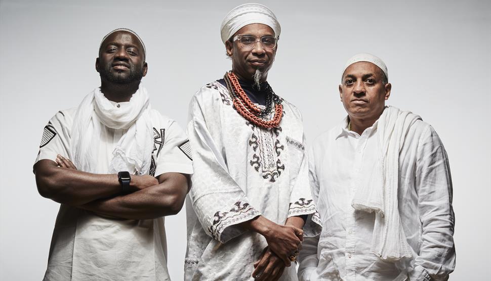 Three men wearing white look towards the camera.