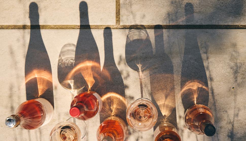 Bottles of wine lined up and their shadows reflected in the sunshine