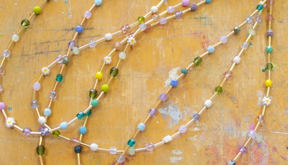 A number of beaded necklaces with different coloured beads.