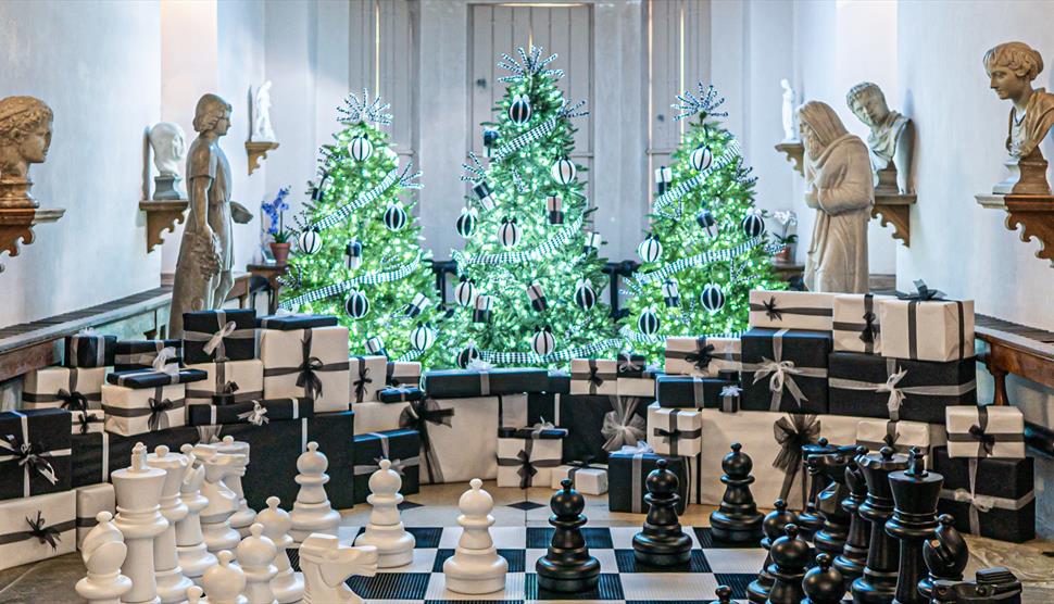 Sparkling Christmas trees illuminate a giant chess board in The Vyne's Stone Gallery.