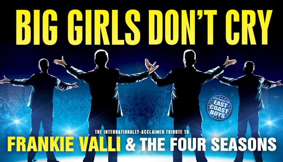 Silhouettes of four men stand on a stage facing the audience