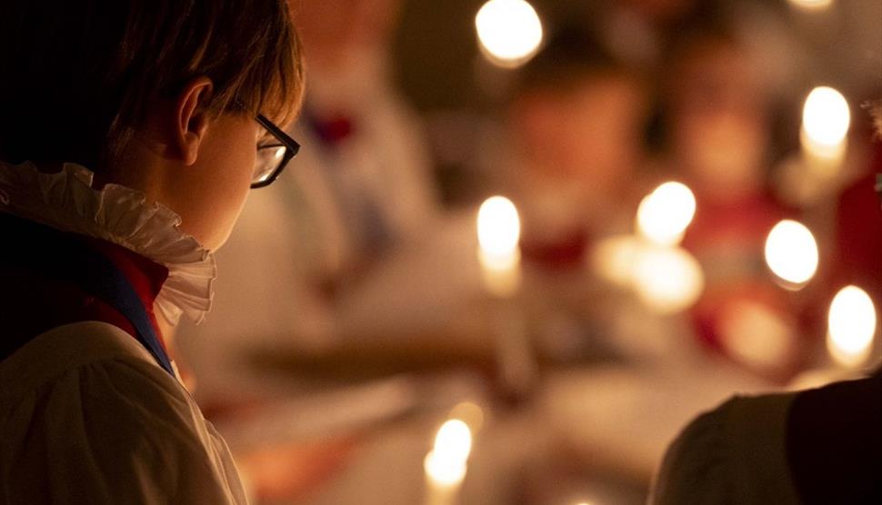 A chorister at Portsmouth Cathedral lit by candles.