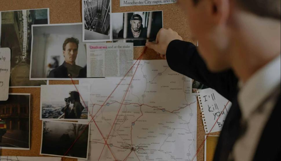 Person examining a map on a bulletin board with various images and notes.