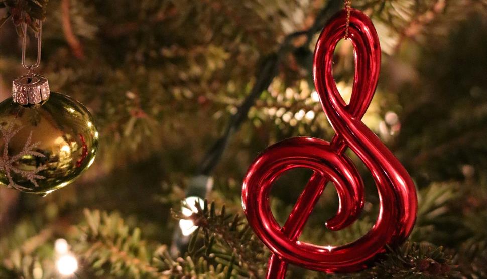 Stock image of a Christmas bauble - shaped like a treble clef - hanging from a tree