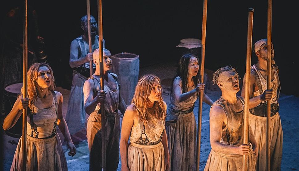 A group of seven actors dressed in rags most holding sticks. From a production of Macbeth.
