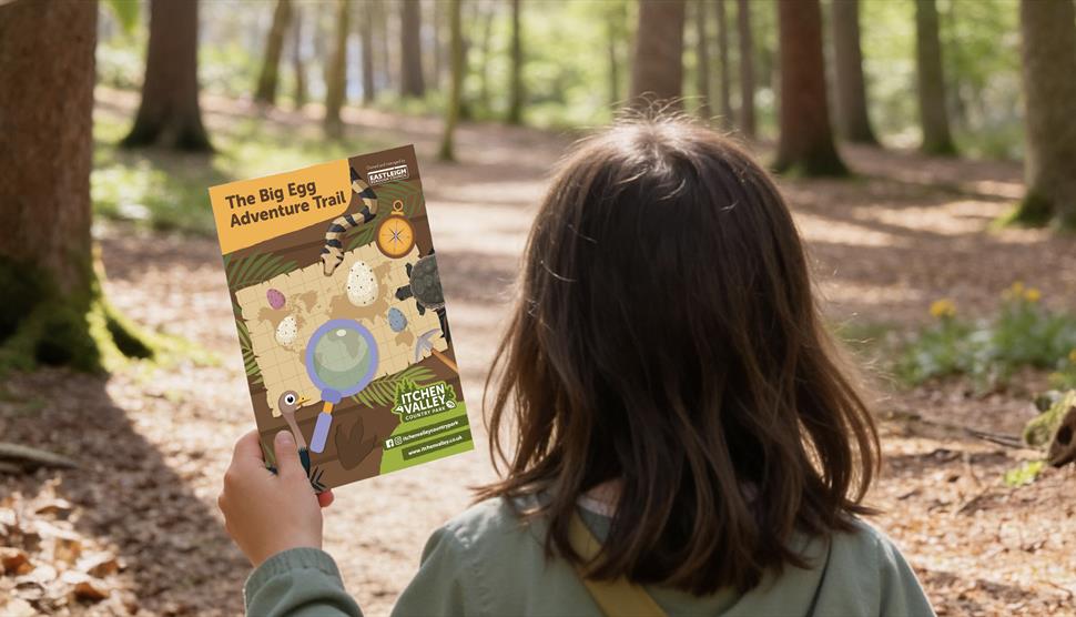 A picture of a child walking on the woodland path holding our Easter trail booklet