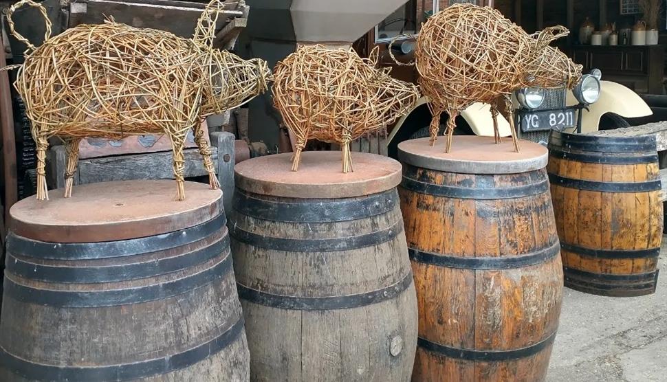 willow pigs in a row standing on wooden barrels