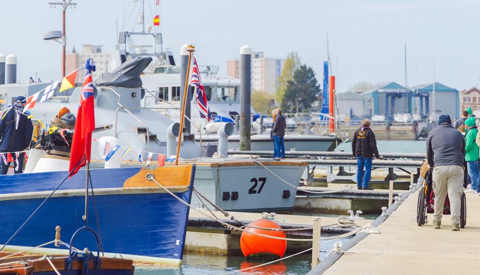 View of the Boathouse 4 pontoon at Portsmouth Historic Dockyard with multiple historic vessels alongside, including Steam Pinnace 199 and MASB 27, and