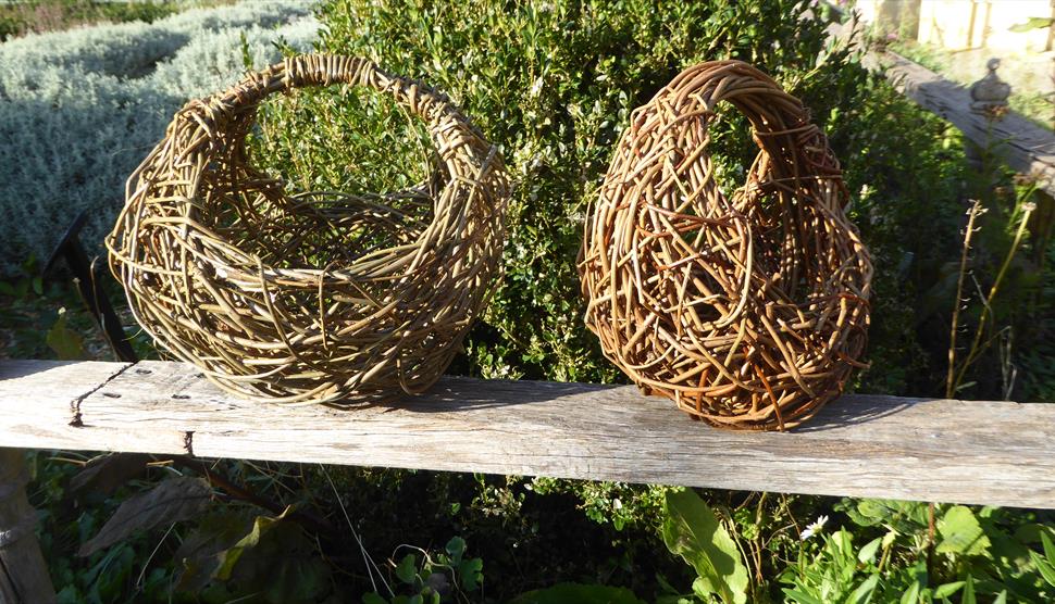 two woven willow baskets sitting on a wall