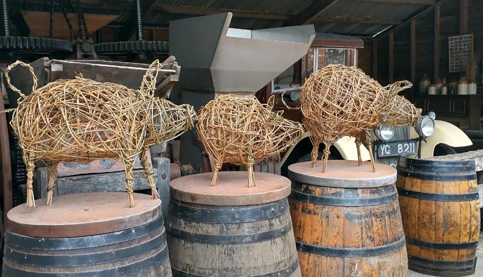 Willow piglet sculptures sitting on wooden cider barrels