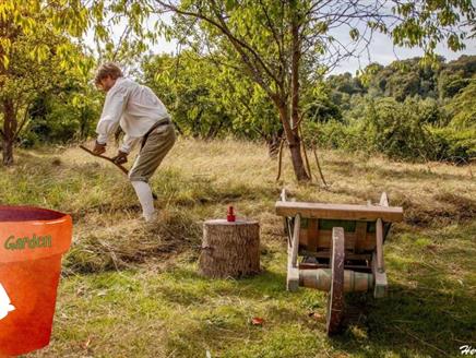 A man in period costume scything