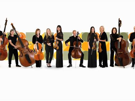 The BSO Strings Ensemble are holding their instruments in front of a background of graphic shapes