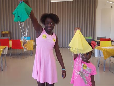 Two girls at The D-Day Story showing off the parachutes they've made