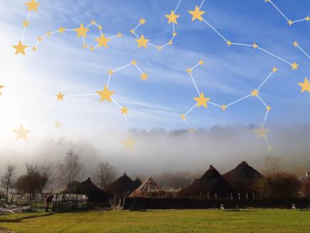 A starry sky of constellations over the roundhouse roofs of Butser Ancient Farm.