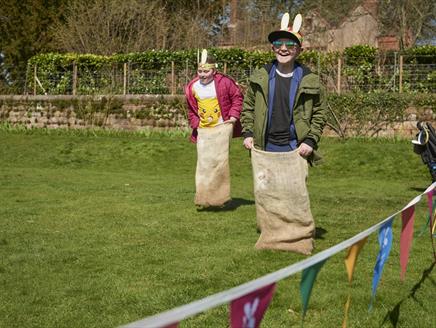 Two children wearing bunny ears, having a sack race.